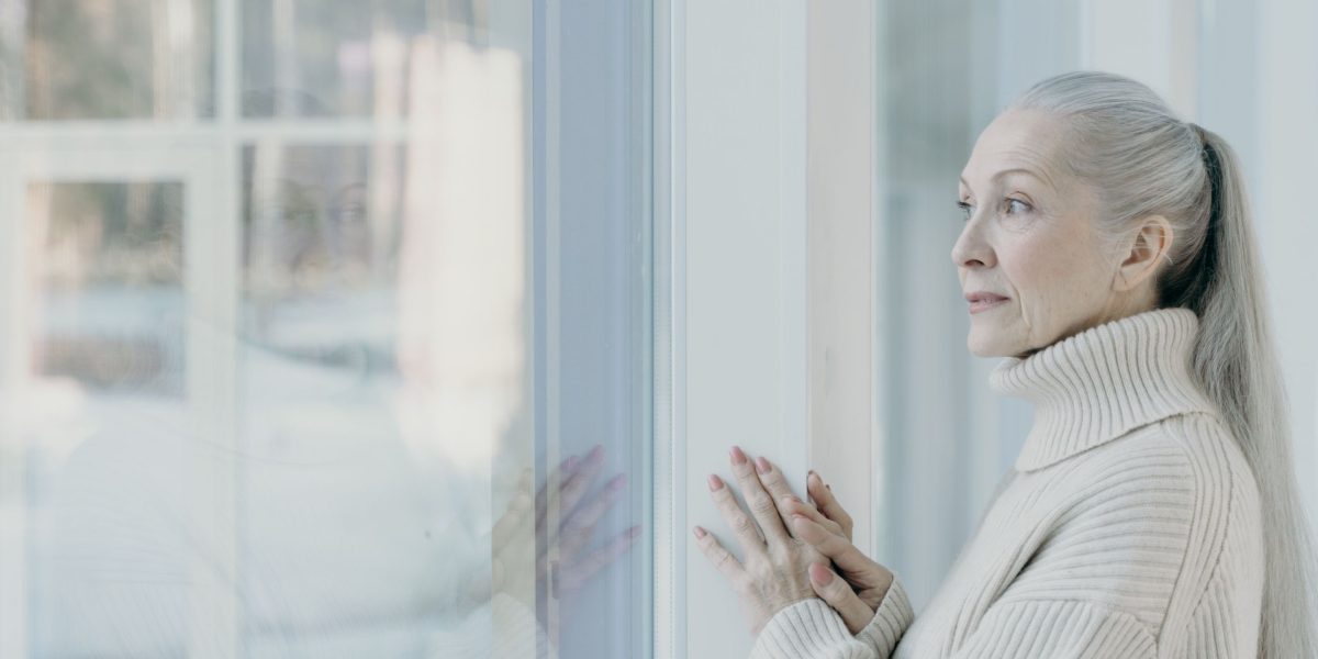 A person deep in thought, appearing contemplative and perhaps burdened, looking out a window.
