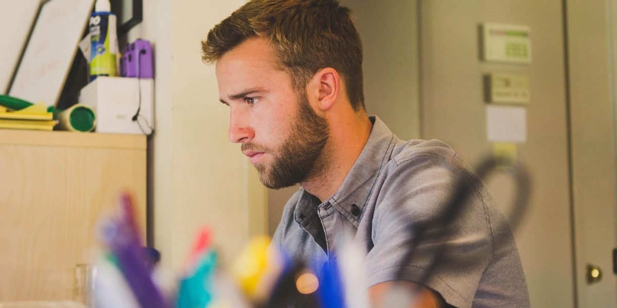 An individual in a bustling office environment, appearing to feel isolated and withdrawn despite being surrounded by others.